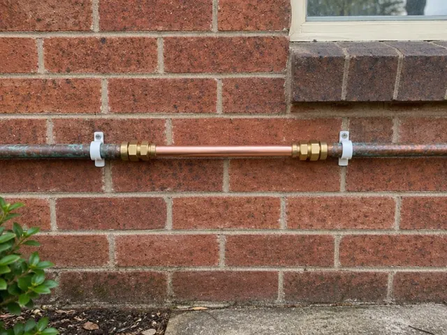 Copper water pipe repair on a brick exterior wall beneath a window in New Lambton