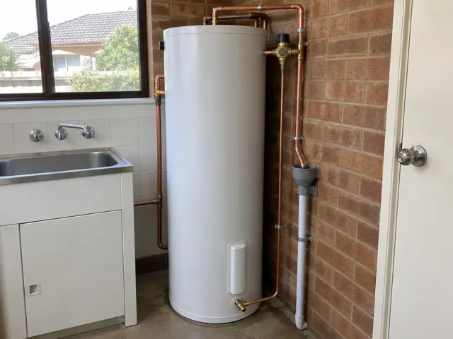 Indoor hot water cylinder beside a sink and brick wall in a utility room in New Lambton